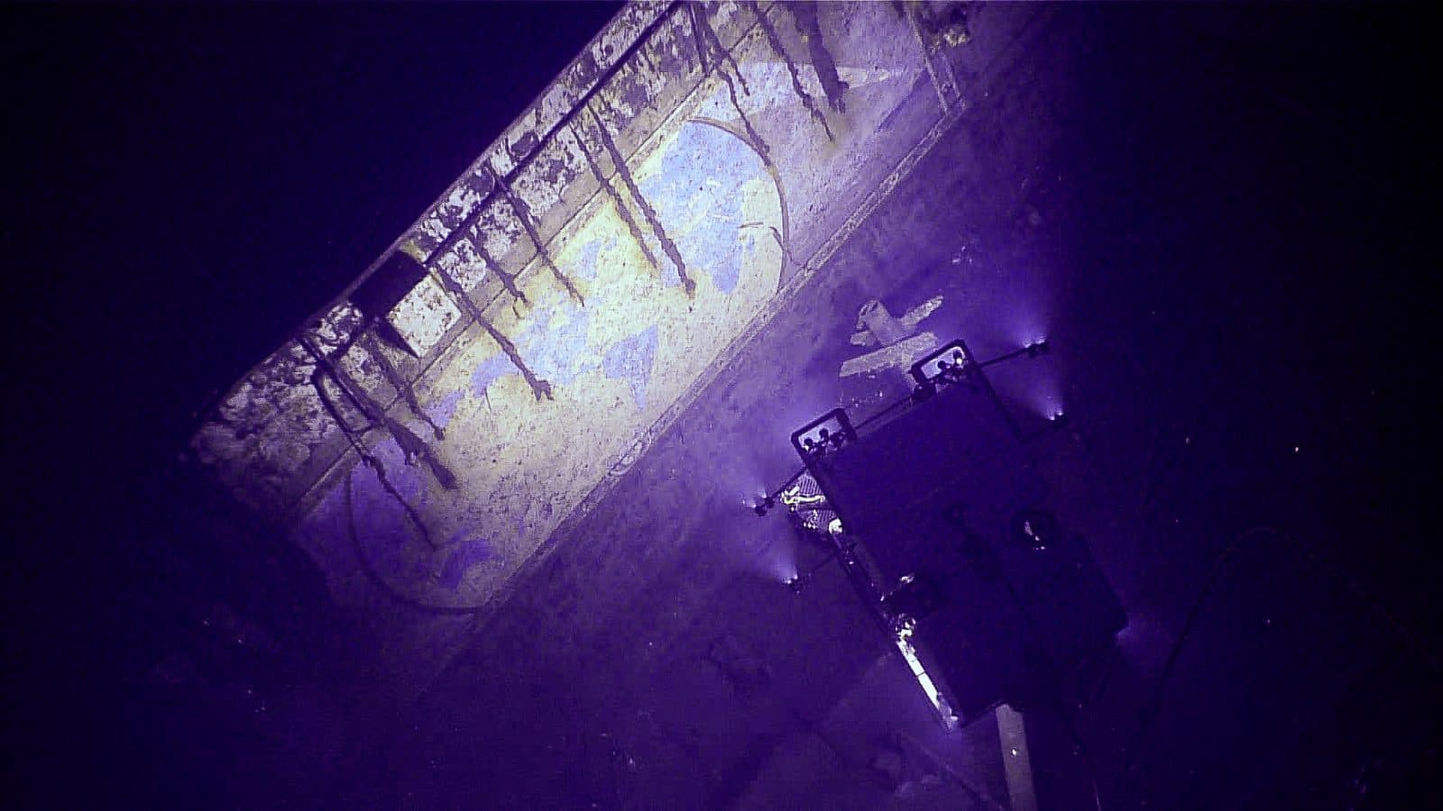 A remotely operated vehicle lighting a hand-painted mural inside a sunken aircraft carrier