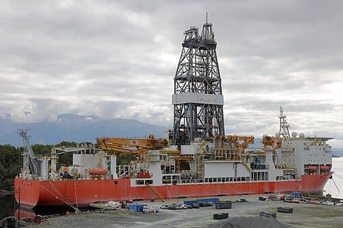 A scientific drilling vessel at sea, its derrick visible amidships